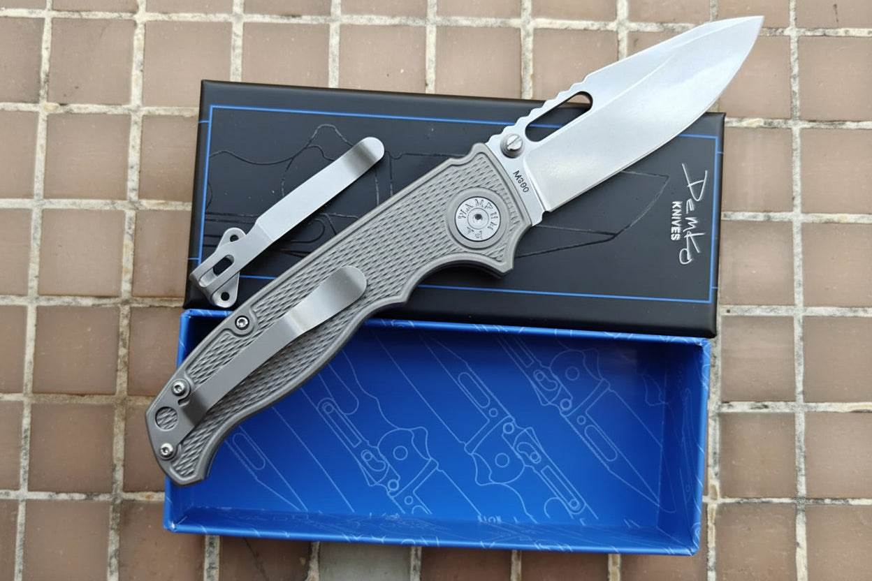 Folding knife with a pocket clip on a blue tray against a tiled wall background