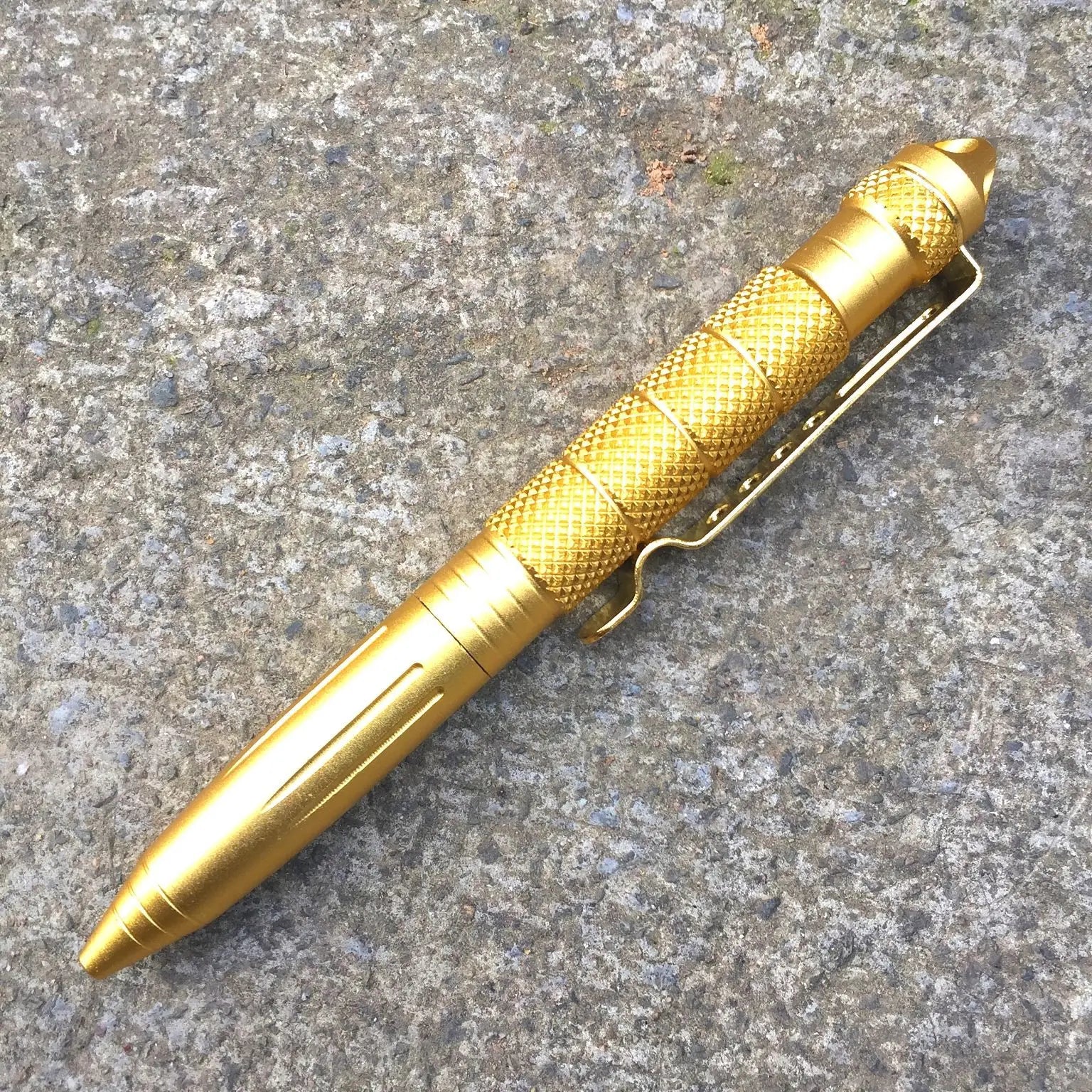 Gold tactical pen on a textured surface