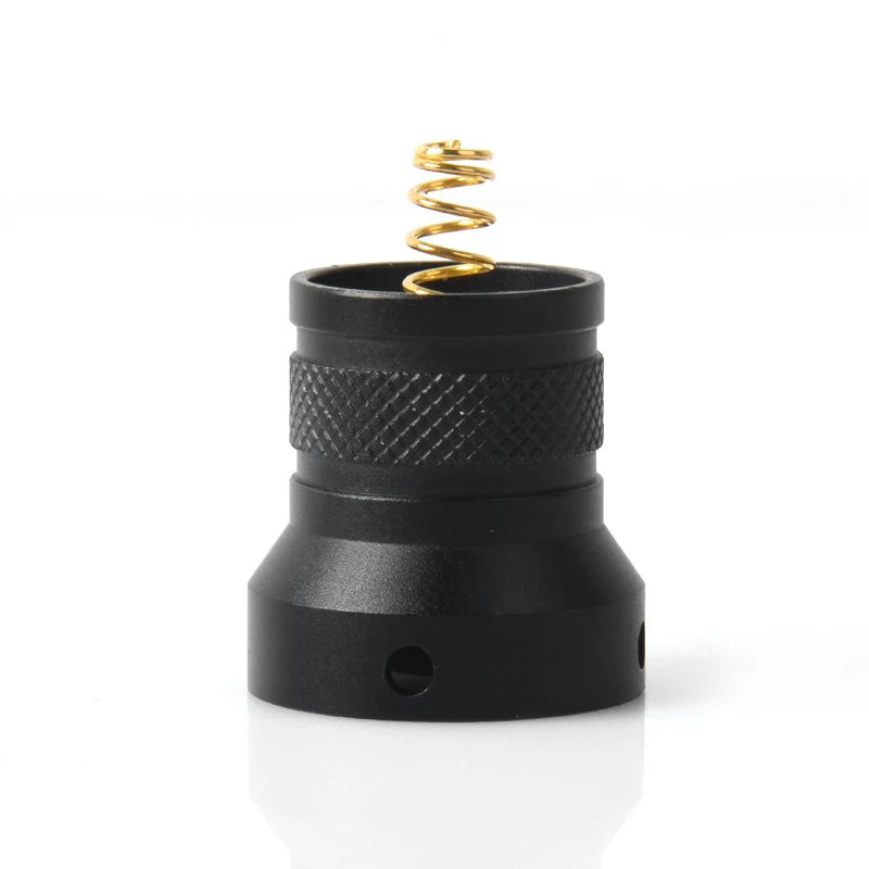 Black cylindrical object with a gold spring on a white background
