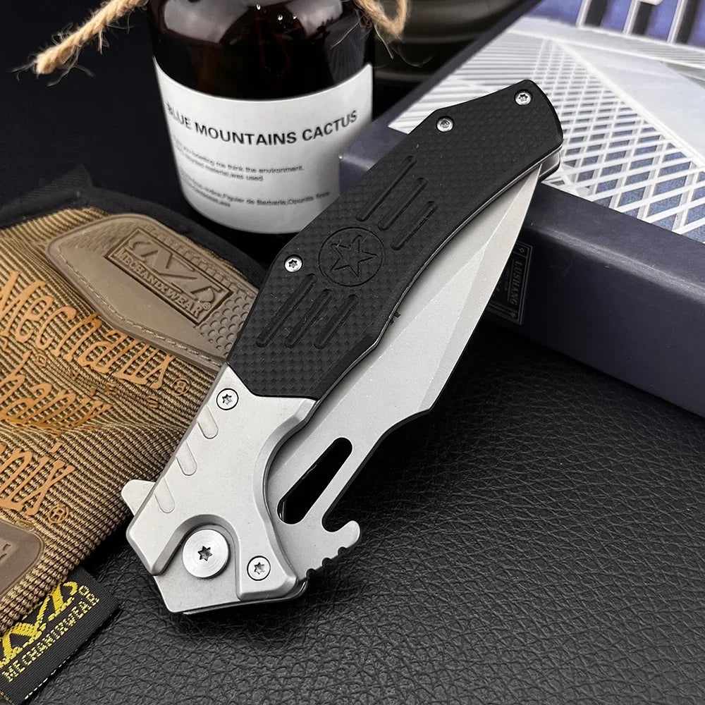 Folding knife with black handle and silver blade on a textured surface with a bottle and pouch in the background.